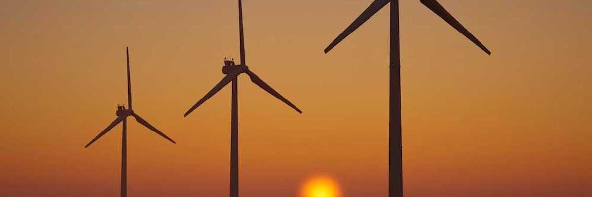 3 offshore wind turbines sillouetted against a setting (or rising) sun