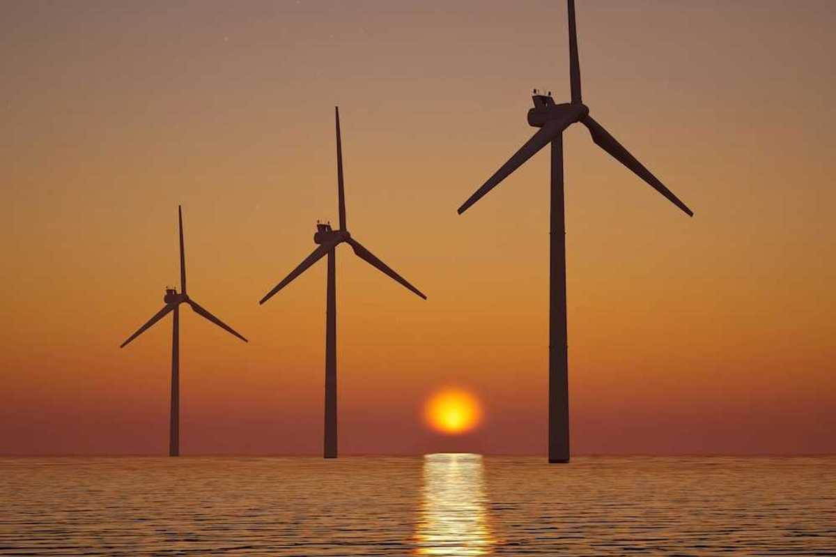 3 offshore wind turbines sillouetted against a setting (or rising) sun