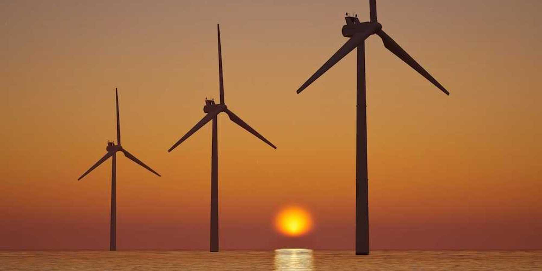 3 offshore wind turbines sillouetted against a setting (or rising) sun