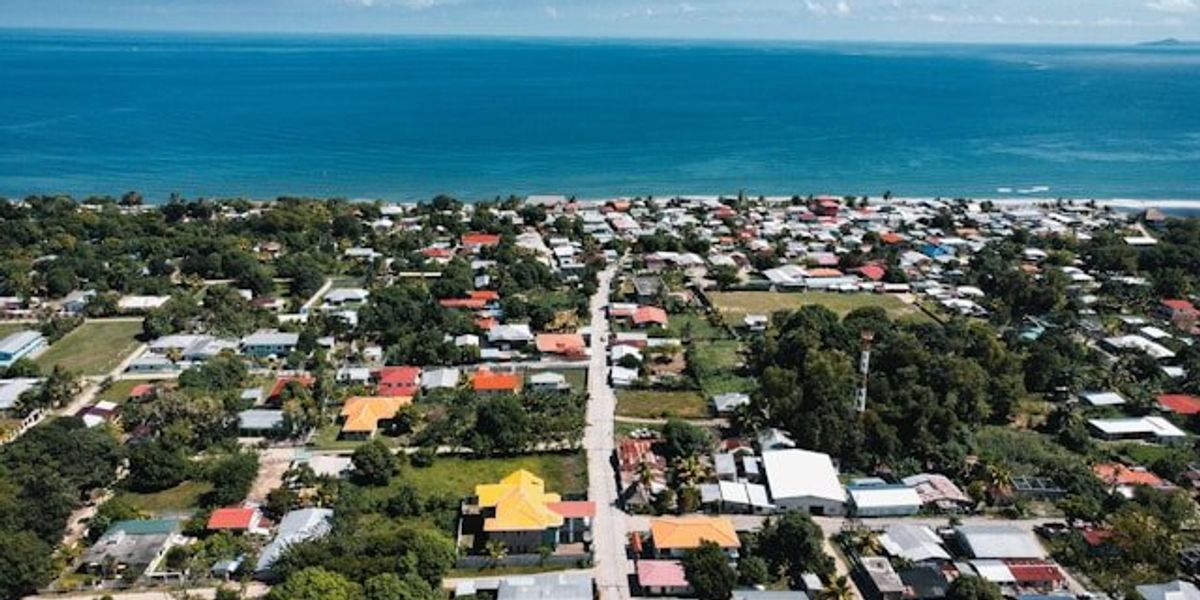 A aerial view of a village on a Pacific Island with ocean in background.
