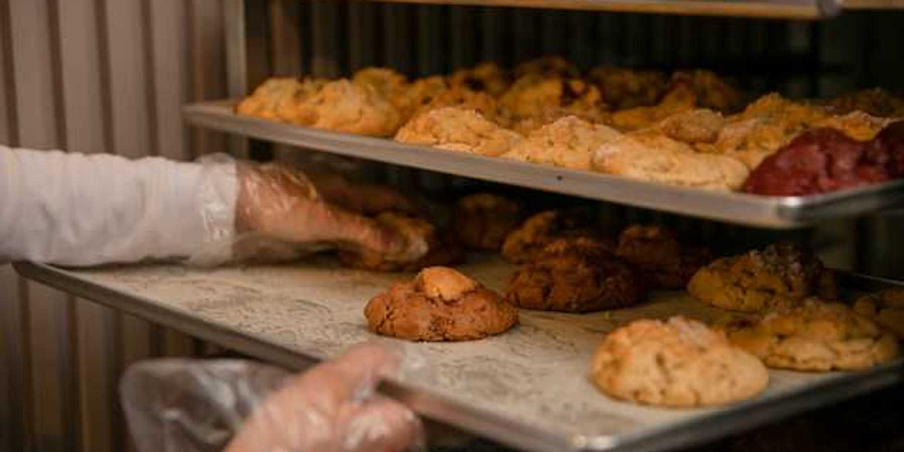 A baker placing baked goods on a tray