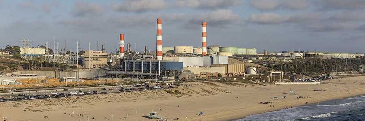 A beach with an oil refinery in the background