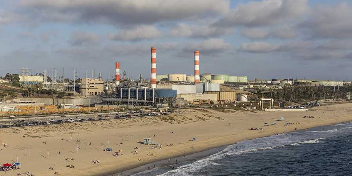A beach with an oil refinery in the background