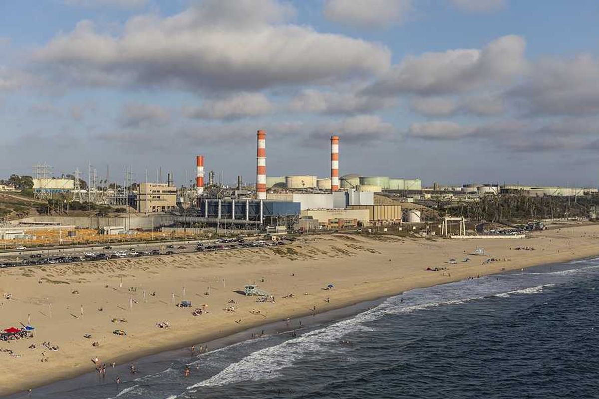 A beach with an oil refinery in the background