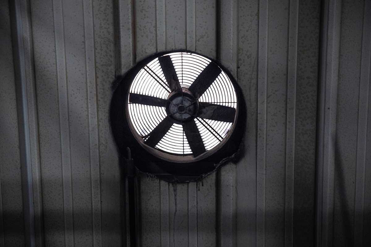 A black and white photo of a circular fan in a wall