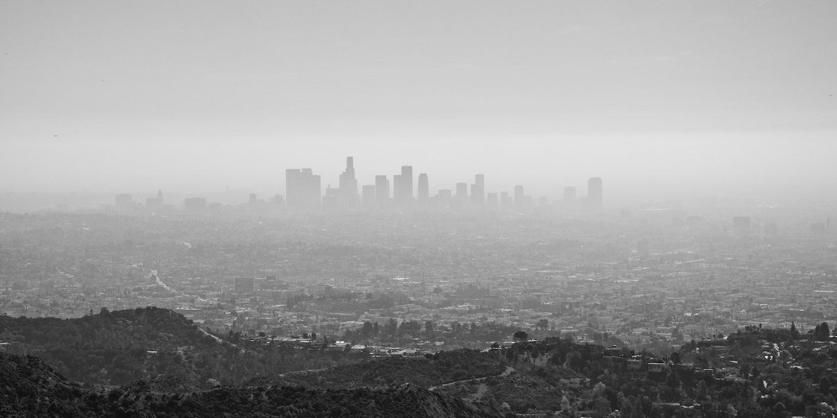 A black-and-white photo of the Los Angeles skyline shrouded in pollution as viewed from nearby mountains.