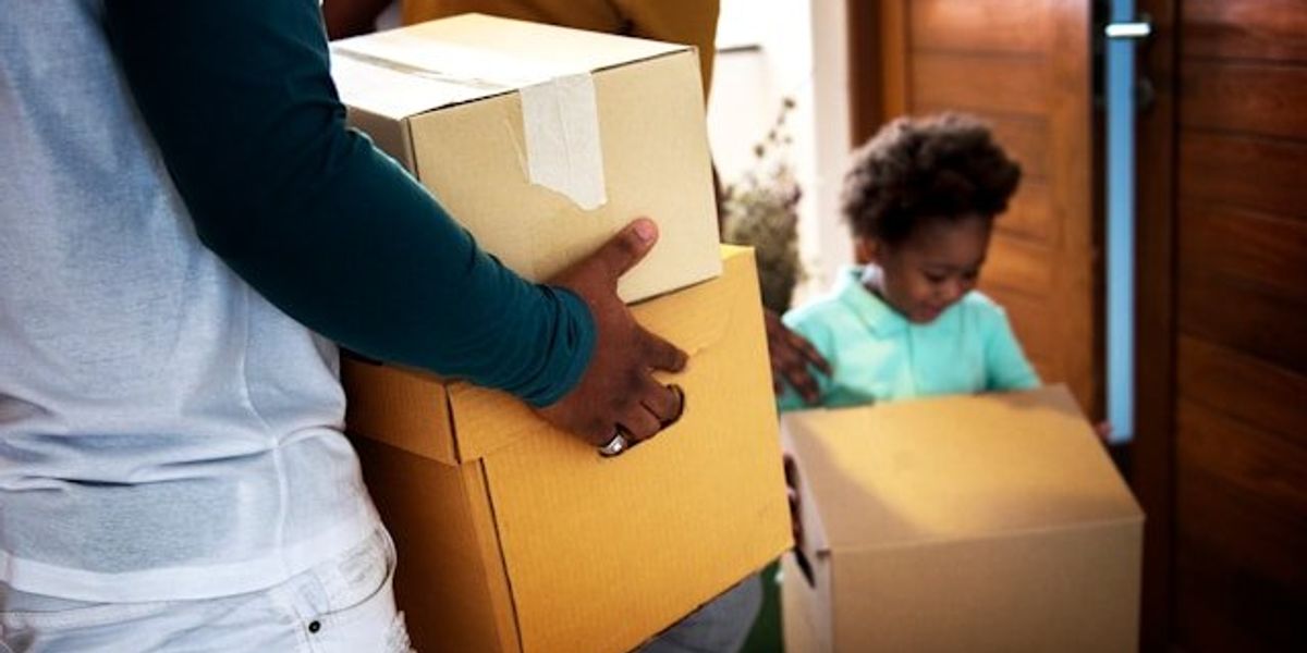 A black family carrying boxes into a house.