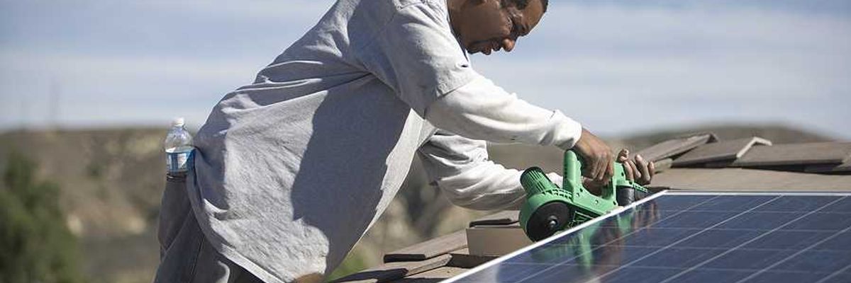 A black man installing solar panels on a roof on a sunny day