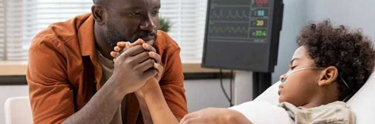 A Black man sitting at the hospital bedside of his son