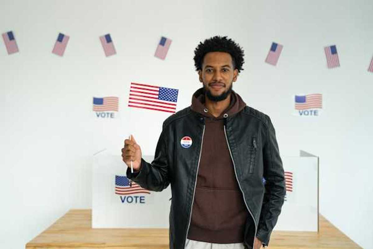 A Black man standing in front of a voting booth