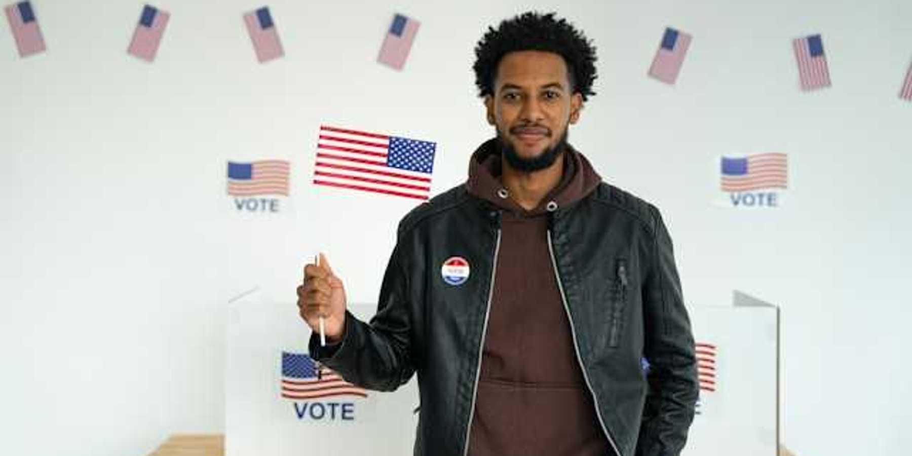 A Black man standing in front of a voting booth