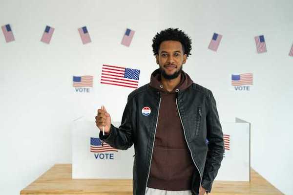 A Black man standing in front of a voting booth