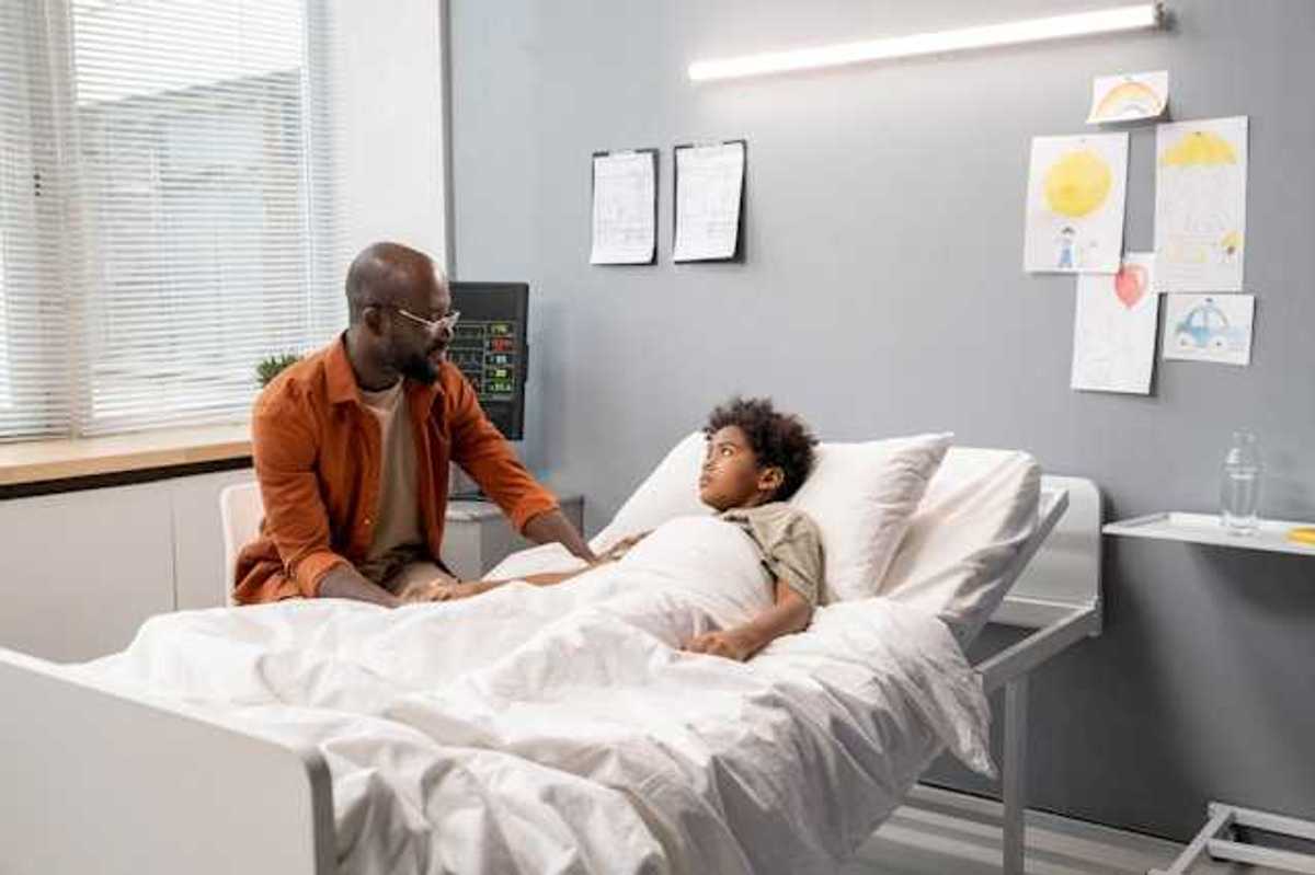 A Black man talking to his child in a hospital bed