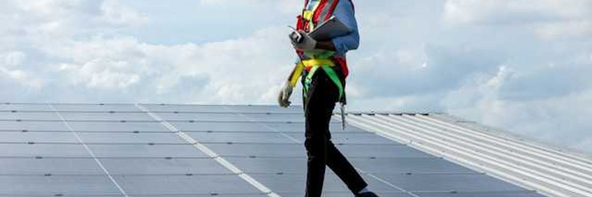 A black man walking on a solar panel installed on a roof