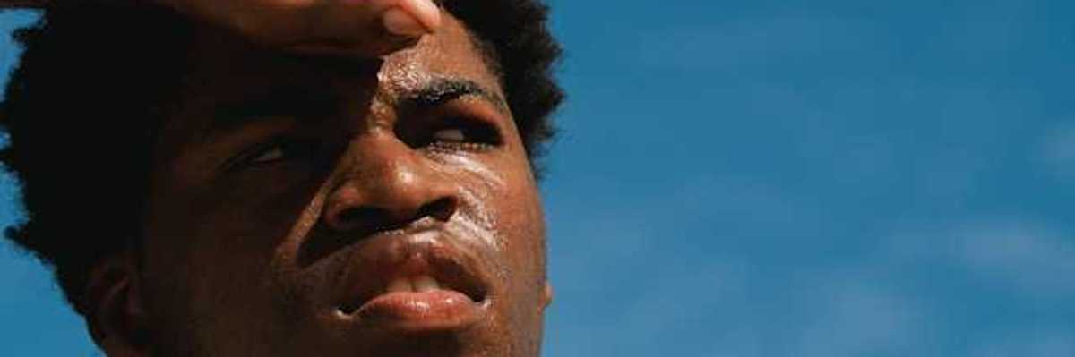 A Black man with perspiration on his face on a sunny day