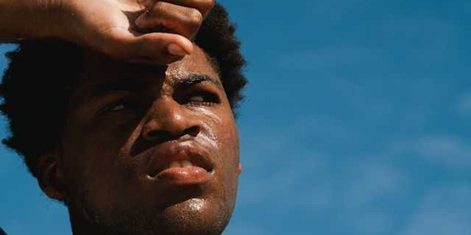 A Black man with perspiration on his face on a sunny day