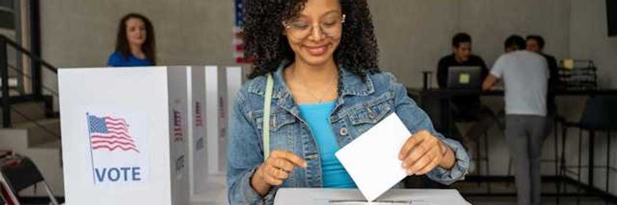 A Black woman putting her voting record into a box at a polling station