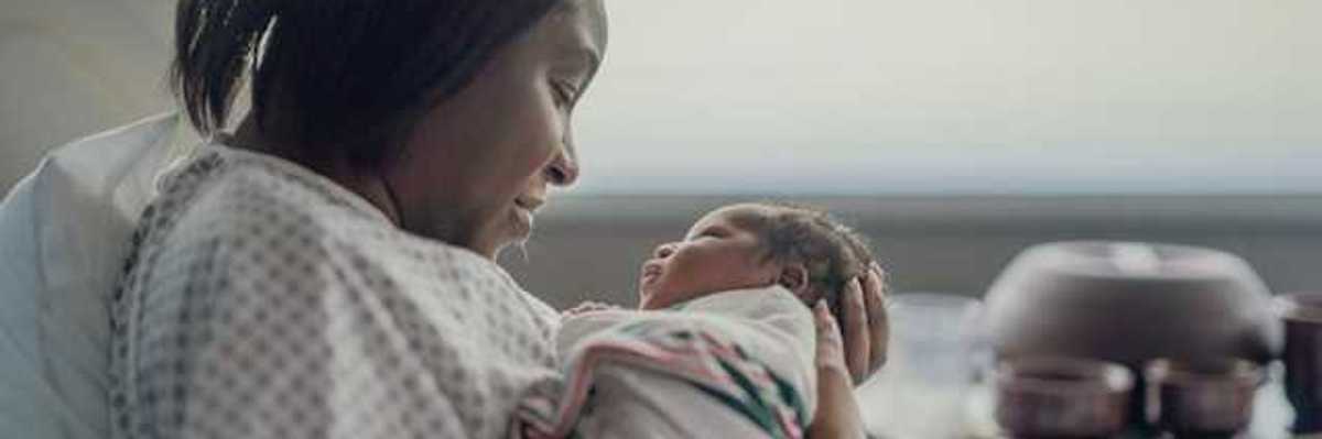 A Black women holding her newborn infant in a hospital room