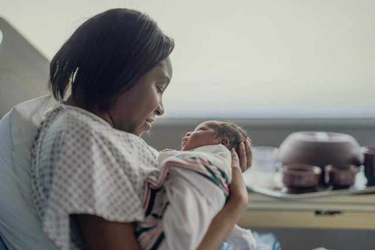 A Black women holding her newborn infant in a hospital room