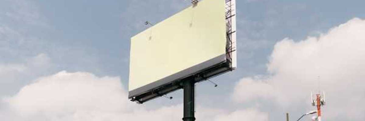 A blank billboard against a blue sky with clouds