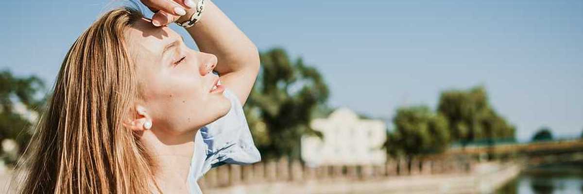 A blonde woman shading her face from the sun