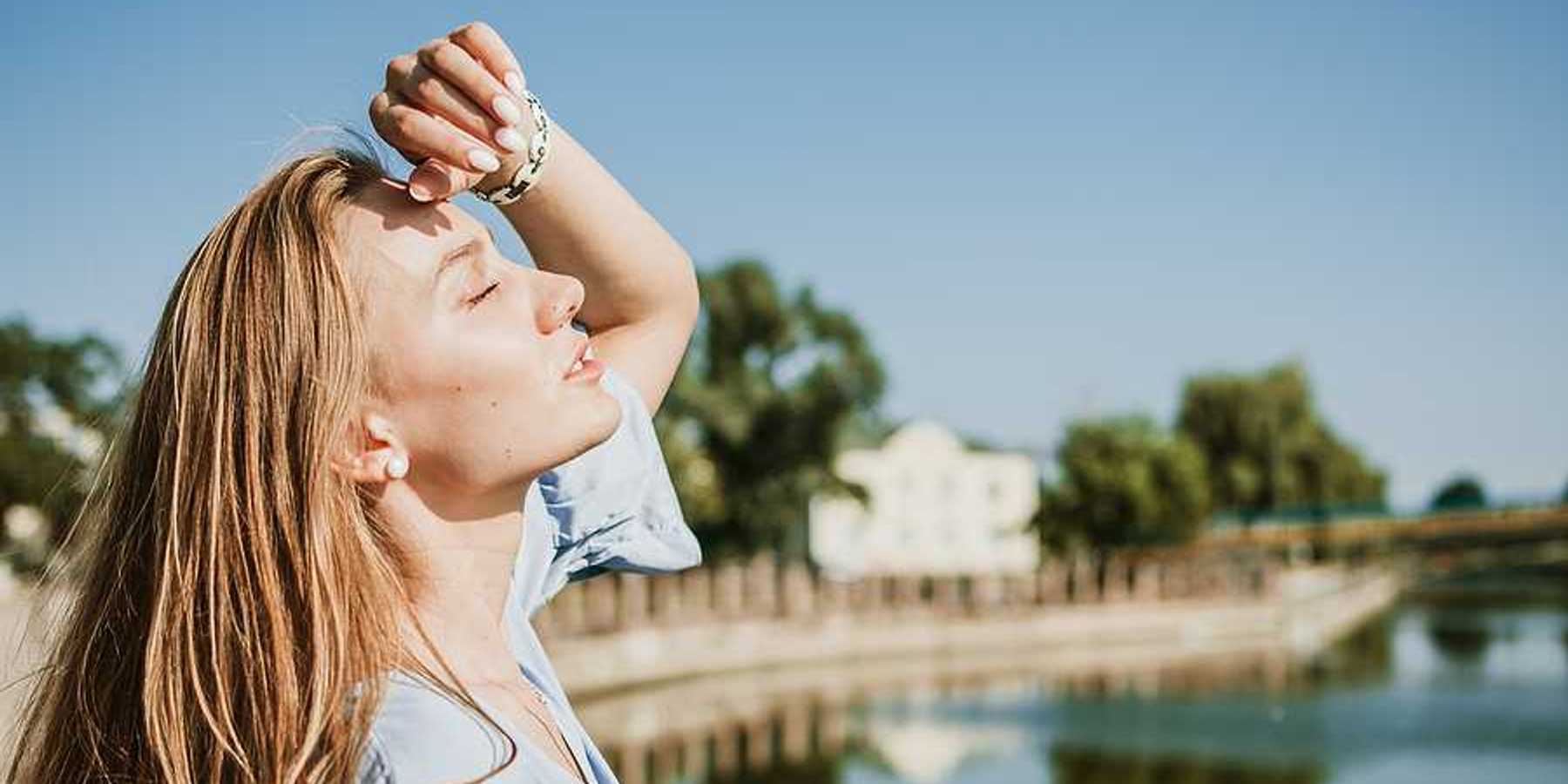 A blonde woman shading her face from the sun