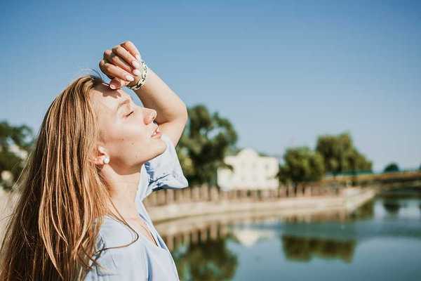 A blonde woman shading her face from the sun