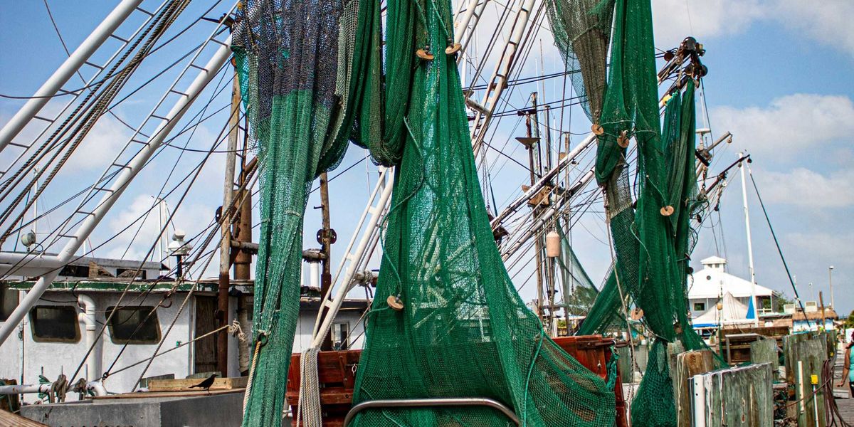 A boat with green fishing nets alongside a dock.