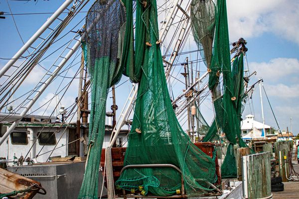 A boat with green fishing nets alongside a dock.