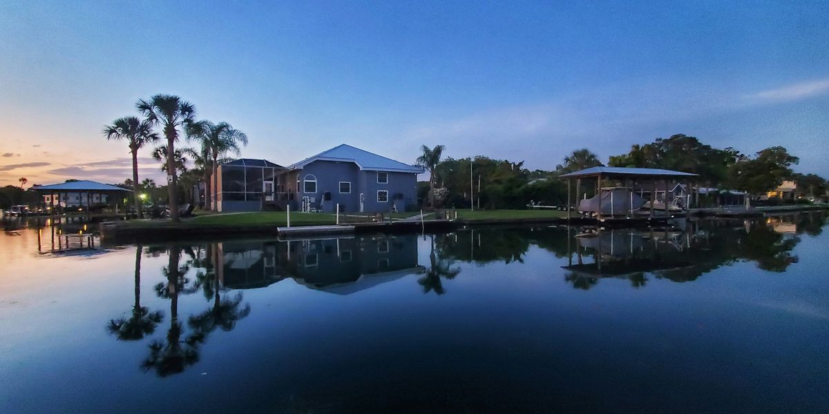 a body of water with buildings and palm trees along it.