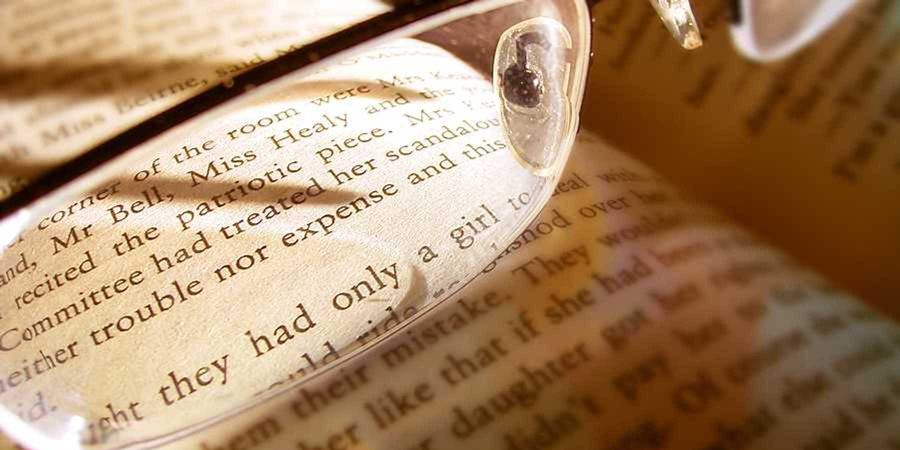 A book with reading glasses magnifying some of the text
