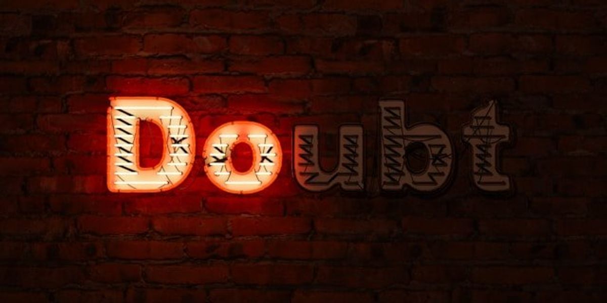 A brick wall with the word Doubt on it, with the D and the O illuminated in red.