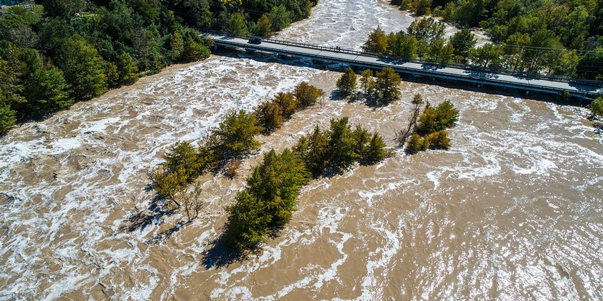 A bridge over a river swollen with flood water.