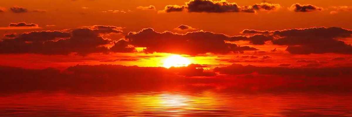 A bright red and orange sunset over water