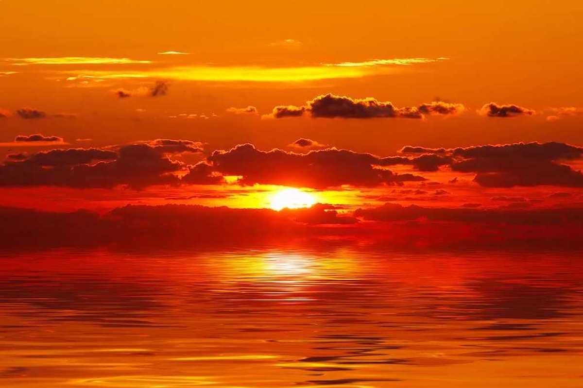 A bright red and orange sunset over water