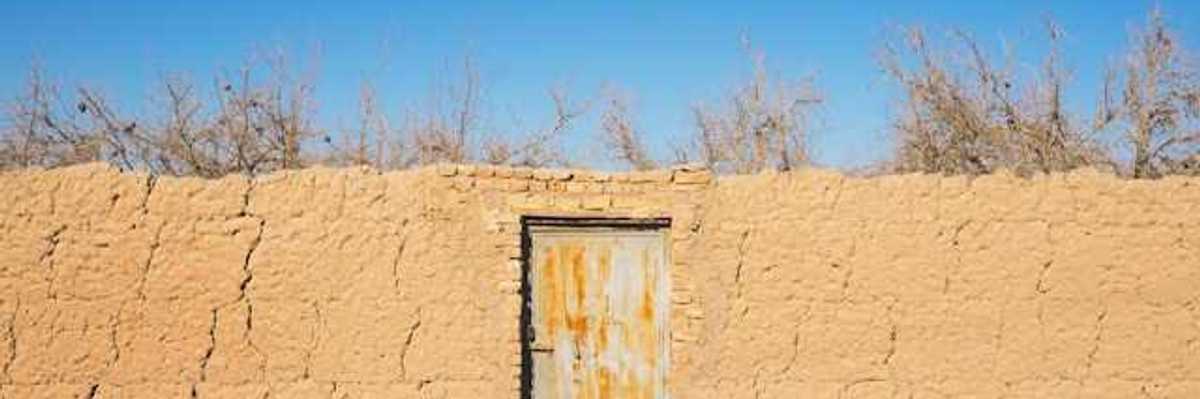 A brown brick wall with a metal door in a dry environment