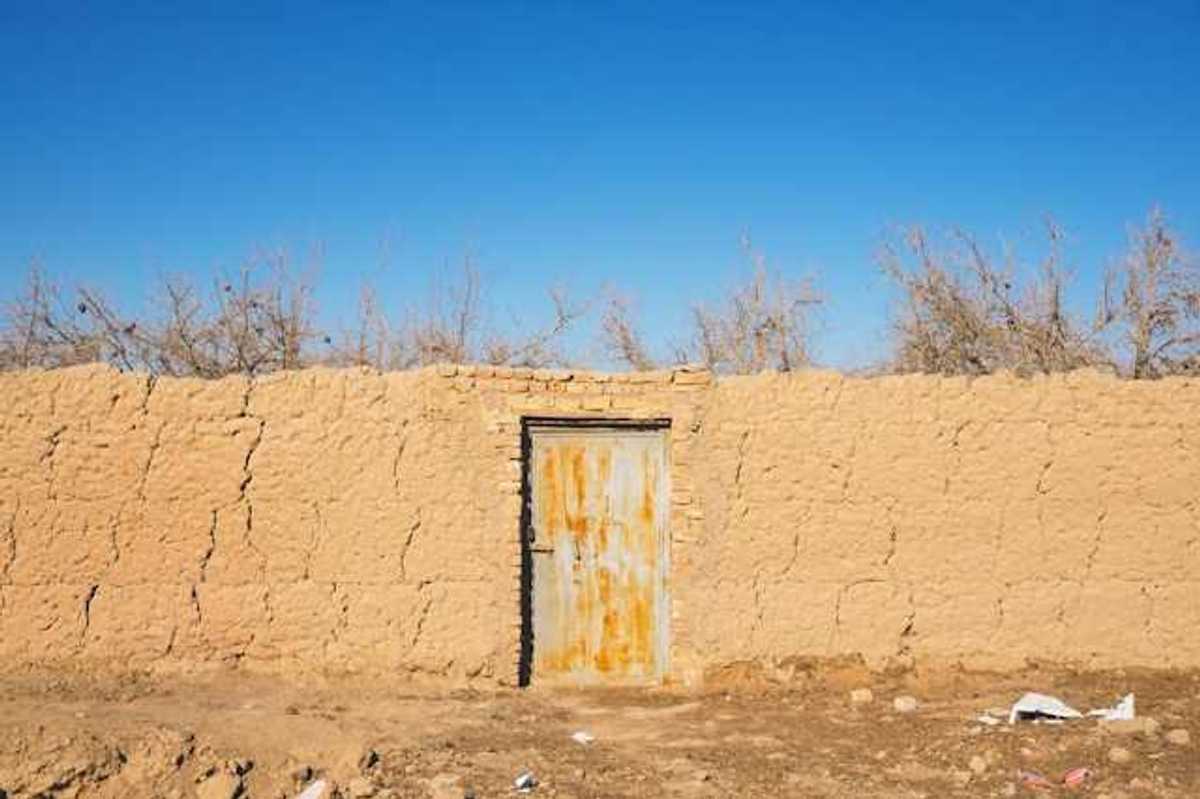 A brown brick wall with a metal door in a dry environment