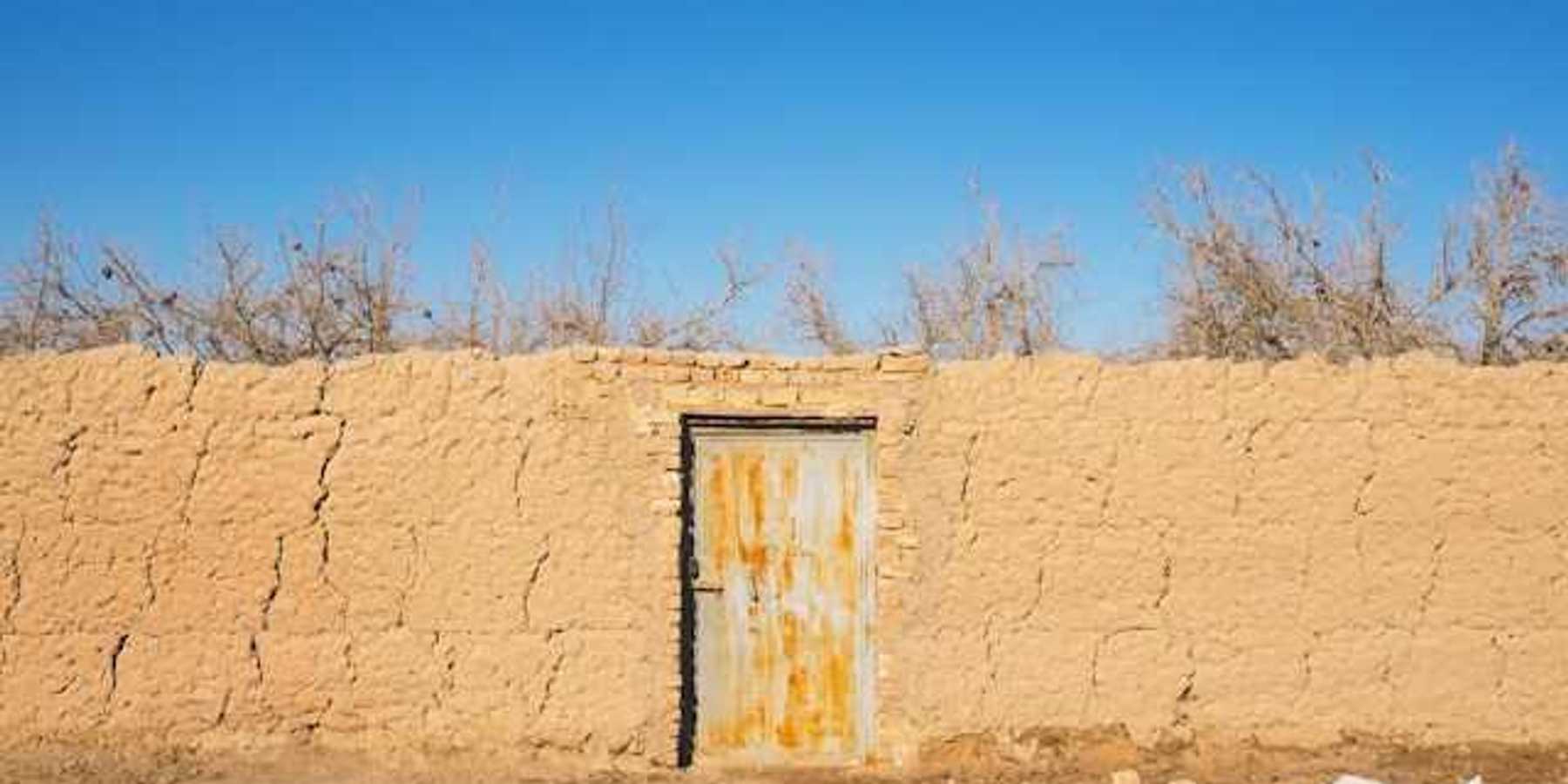 A brown brick wall with a metal door in a dry environment