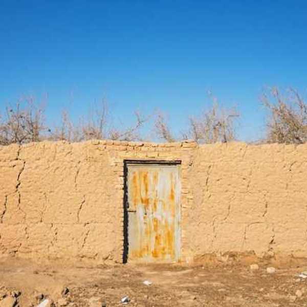 A brown brick wall with a metal door in a dry environment