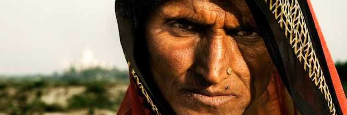 A brown-skinned woman in a colorful veil on a sunny day looking at the camera