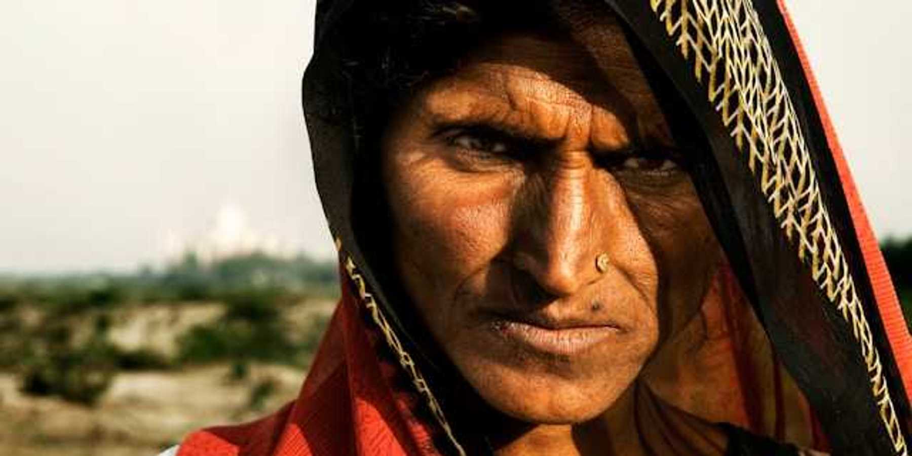 A brown-skinned woman in a colorful veil on a sunny day looking at the camera