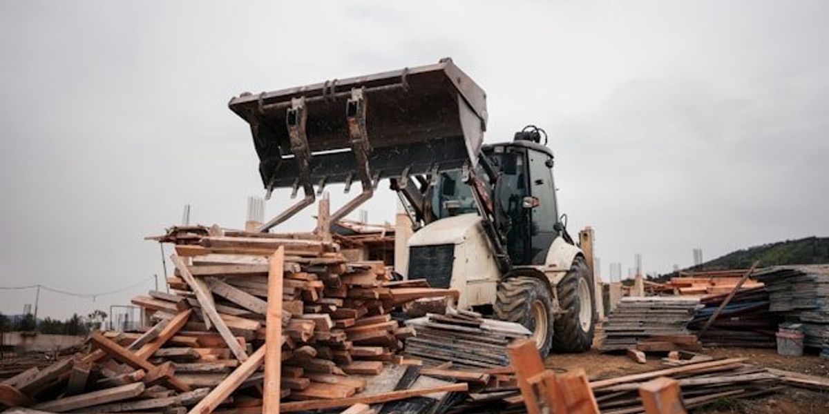 A bulldozer gathering wood and other construction materials.