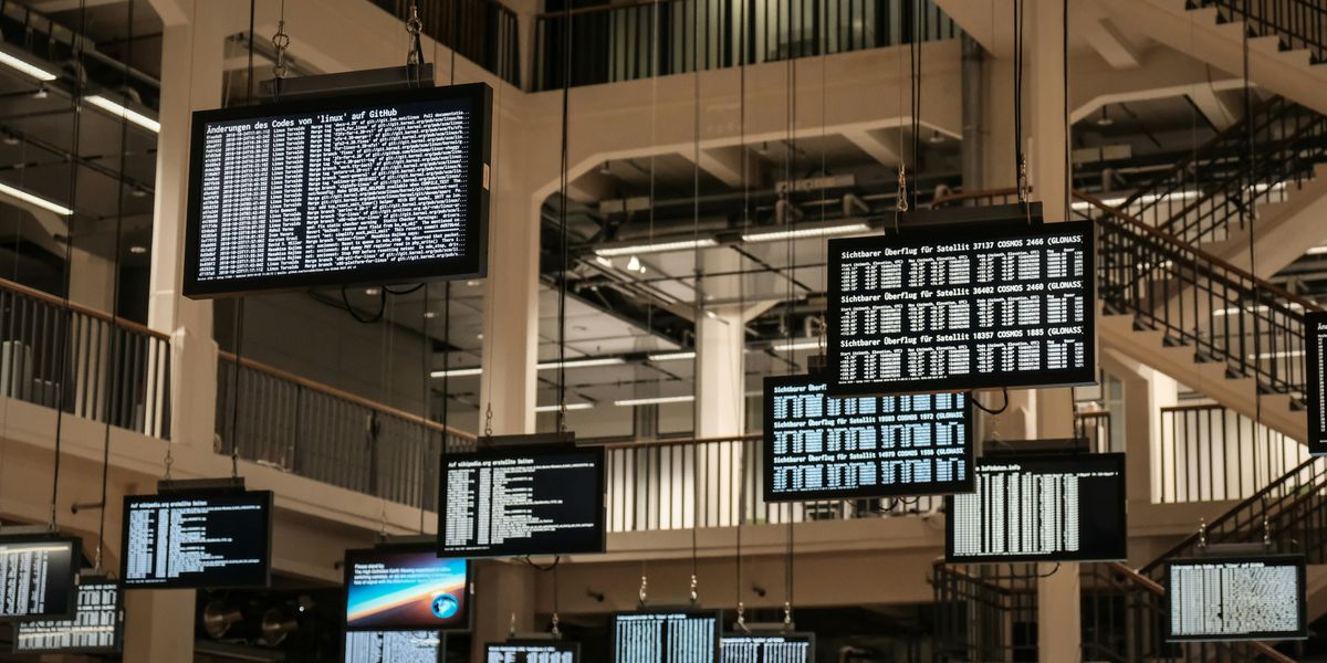 a bunch of television screens hanging from the ceiling.