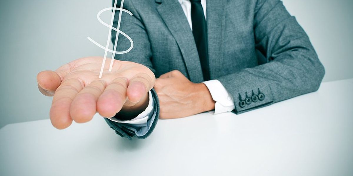 A business man holding his hand out with an illustration of a dollar sign hovering above his palm.