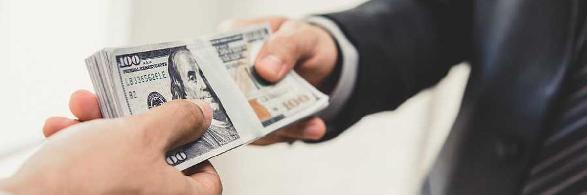 A businessman handing US hundred dollar bill over to another businessman