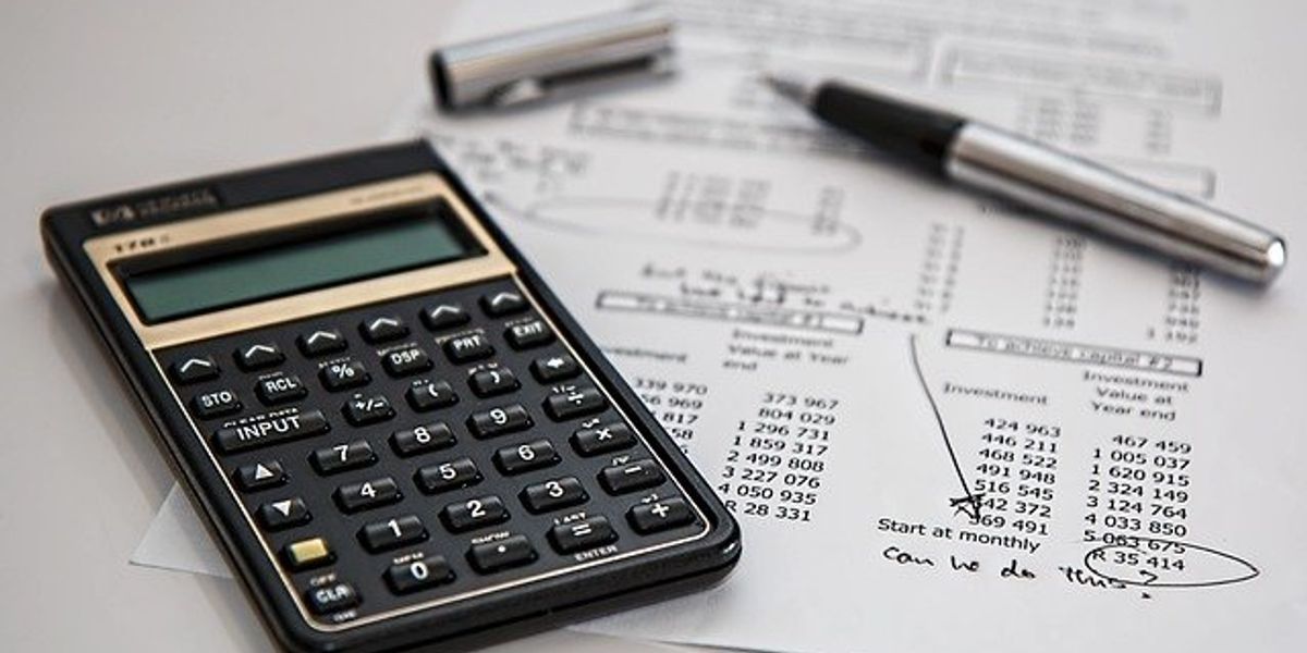 A calculator sitting on top of a piece of paper with numbers listed in columns.