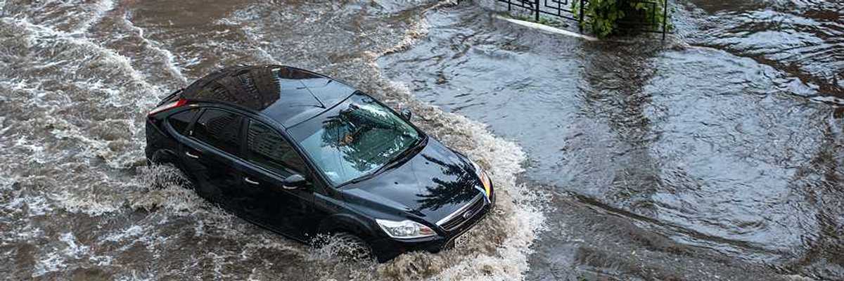 A car driving through floodwaters in a city after a heavy rain