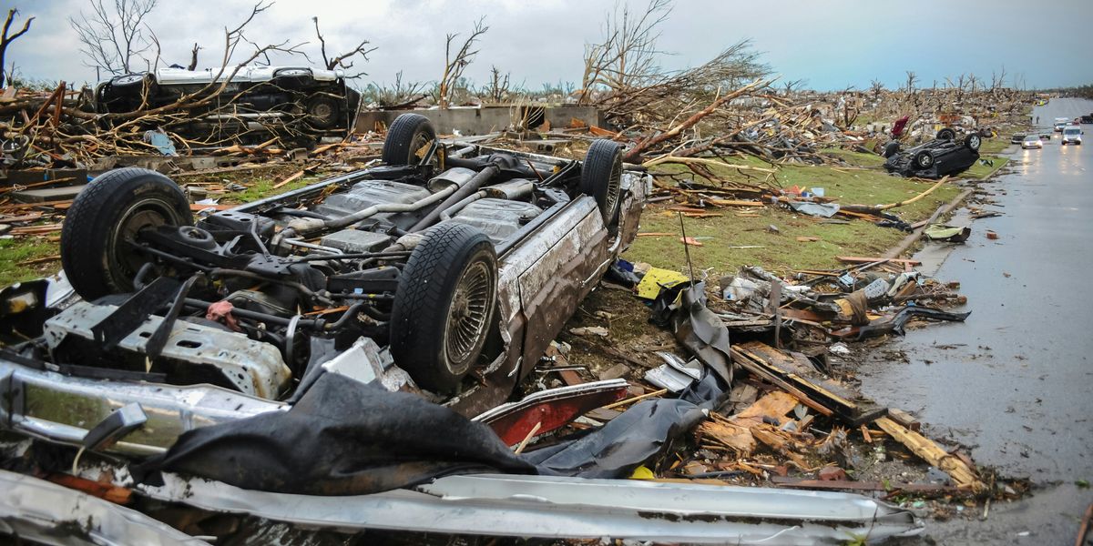 a car that is sitting upside down on top of a pile of debris after a tornado.