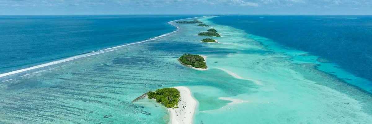 A chain of islands uninhabited in Tha Atoll Maldives. Green islands against turqoise sea.