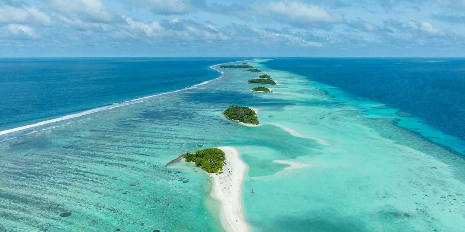 A chain of islands uninhabited in Tha Atoll Maldives. Green islands against turqoise sea.